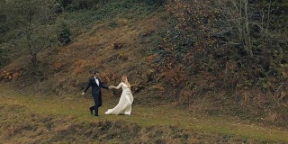 一对年轻美丽的新婚夫妇一起漫步在秋天的环境中。结婚的那一天。慢动作