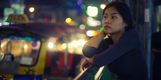 年轻的亚洲女人站在夜城的街道上
