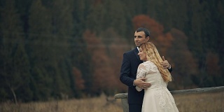 一对年轻美丽的新婚夫妇共同站在秋天的森林前。结婚的那一天。慢动作