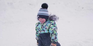 一个小孩在雪山上玩，扔雪，笑。阳光明媚的一天。新鲜的空气里充满了乐趣和游戏。