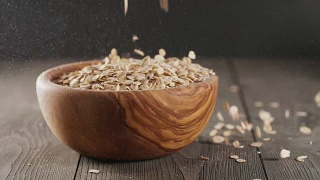 燕麦片落入木橄榄碗的特写慢镜头视频素材模板下载