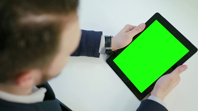 一名男子使用绿色屏幕的数字平板电脑