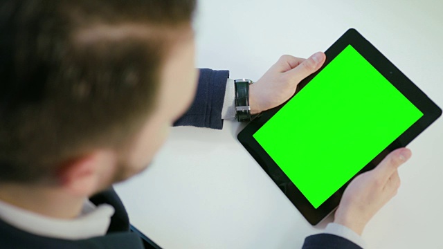 一名男子使用绿色屏幕的数字平板电脑