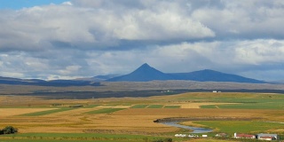 农田，蜿蜒的河流和黑暗的高山背景，冰岛的风景