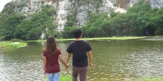 Man and woman or couple walk together holding hands in nature with mountain and river. Happy freedom and travel concept.