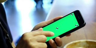 近距离的女人拿着手机与标记绿色屏幕幻灯片屏幕在咖啡店的桌子上