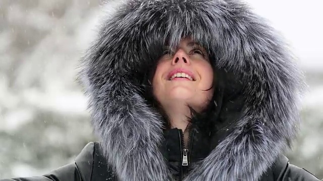 年轻漂亮的女子在暴风雪中穿着皮大衣