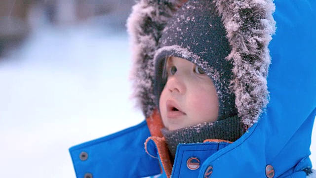 可爱的小男孩在暴风雪中穿着皮大衣