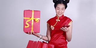 女人穿旗袍，用手机购物袋和礼盒