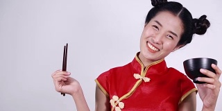快乐的女人穿着中国旗袍，带着筷子和碗