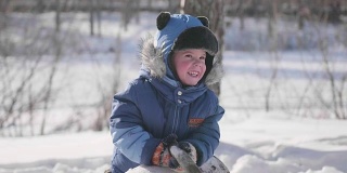 一个小孩在冬天的公园里玩耍，笑着。阳光明媚的一天。新鲜的空气里充满了乐趣和游戏。