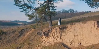 一对年轻美丽的新婚夫妇一起站在山坡上。结婚的那一天。空中拍摄