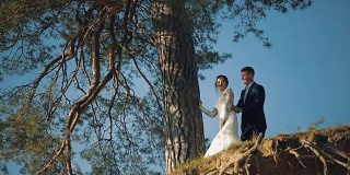 一对年轻美丽的新婚夫妇一起站在山坡上。结婚的那一天。慢动作