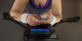 胖女人一边骑健身自行车一边刷手机，健身应用