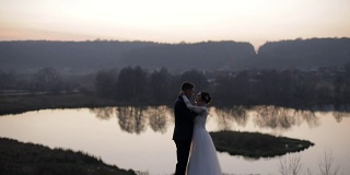 一对年轻美丽的新婚夫妇站在湖边。结婚的那一天。慢动作