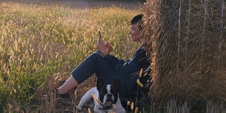 吉尔在草地上，法国斗牛犬拿着智能手机。