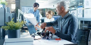 电子工程师与机器人一起工作，用笔记本电脑处理机器人的响应和检查数据。有专家工作的计算机科学研究实验室。