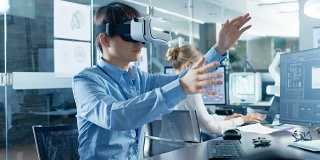 计算机科学工程师戴着虚拟现实耳机与3D建模，做手势。在后台工程局和忙碌的工人一起工作。