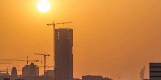 在卡塔尔多哈，一座正在建设中的塔楼，映衬着夕阳的轮廓