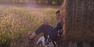 吉尔在草地上，法国斗牛犬拿着智能手机。