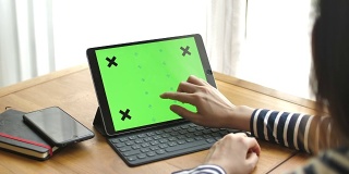 Young woman using digital tablet with a green screen