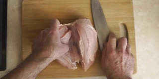 男人把鸡胸肉切成两半