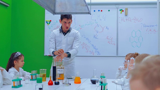 年轻的男孩和女孩们正在做化学实验。老师和小朋友在上化学课