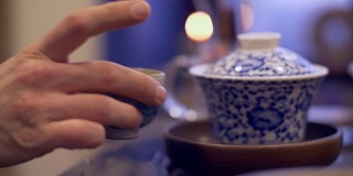 男性用手将热水倒入碗中冲泡茶叶。男子手拿茶杯
