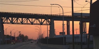 近景:日落时分，在工业城镇繁忙的高速公路上行驶的汽车剪影