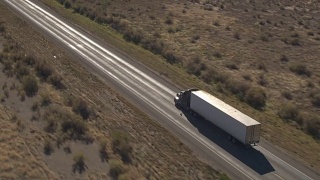 空中特写:无牌货运半挂车在沙漠中运输货物视频素材模板下载