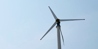 在阳光明媚的日子里仰望风力涡轮机。风车产生电子城市