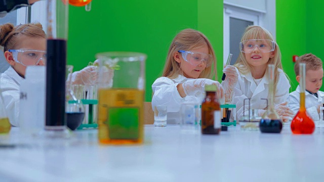 孩子们在学校的实验室里学习化学。一组孩子在化学课上做实验