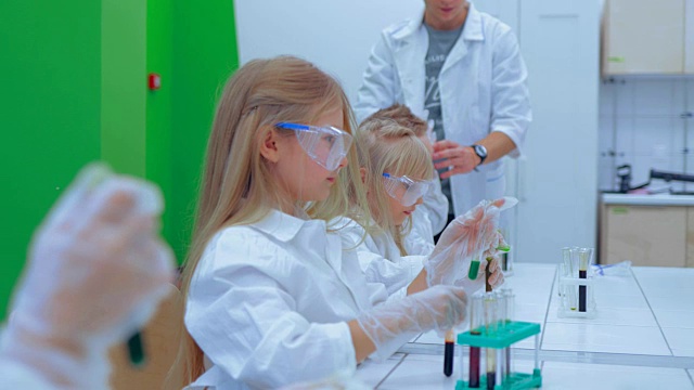 老师和学生在学校教室里做科学实验。化学课上的孩子们