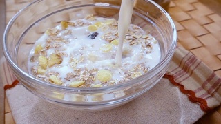 全谷物麦片早餐在碗里，美味的早餐和牛奶。慢动作旋转跟踪镜头。视频素材模板下载