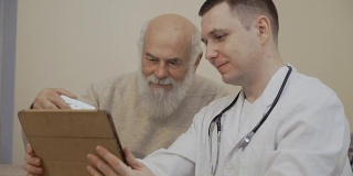老男人拿着一盘药丸问医生与数字平板