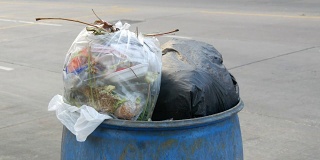 满垃圾桶的大垃圾袋装满了剩菜和垃圾在街上