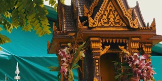 在一个花园里，棕色的佛坛供祈祷者使用，上面装饰着鲜花和各种小雕像