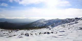 冬季的山脉景色，云和阴影笼罩着雪景。视频。雪山和阳光灿烂。山坡和山脊上覆盖着新鲜的粉状雪