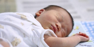 把注意力转移到宝宝身上。安静的亚洲女婴躺在床上，在卧室里睡觉。