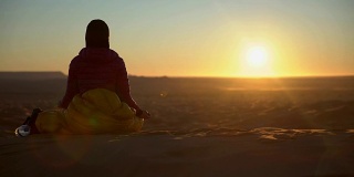 在沙漠日落前沉思的女人