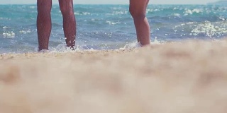 一对情侣在海边的沙滩上。一对夫妇站在海边，脚上全是水。夏天和放松的概念。缓慢的运动。1920 x1080