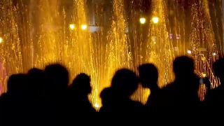 游客在晚上欣赏灯光喷泉，前景是剪影视频素材模板下载
