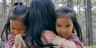 两个亚洲女孩跑到妈妈身边，深情地拥抱，慢镜头