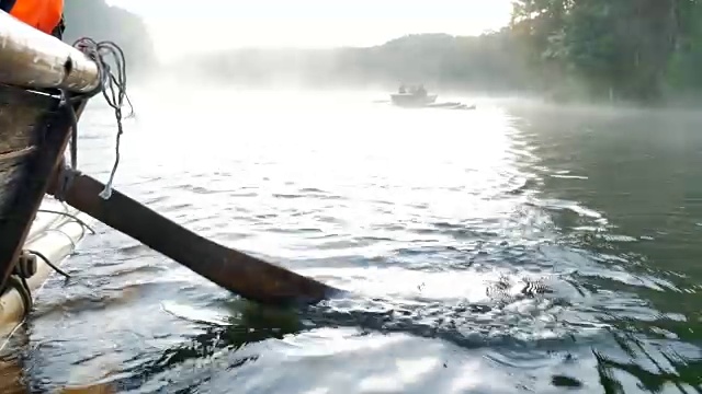 近距离观看木船划桨在竹筏通过雾漂浮在湖面上在早上在庞ung, Mae Hong Son，泰国