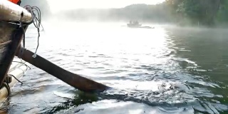 近距离观看木船划桨在竹筏通过雾漂浮在湖面上在早上在庞ung, Mae Hong Son，泰国