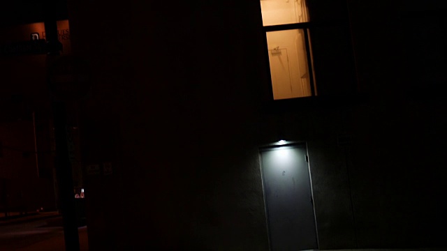 夜间，镜头移向巷子附近的可疑城市门口，灯光昏暗