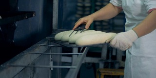 一名工人正在准备面包，准备存放和做表面切割。