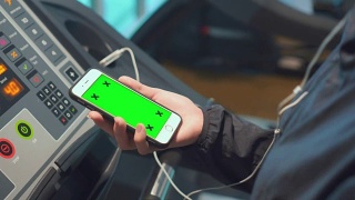 女性在健身房使用智能手机，绿色屏幕视频素材模板下载