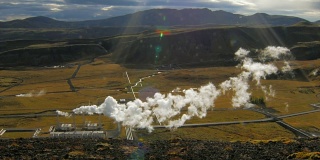 冰岛山谷景观与山脉和地热发电厂与蒸汽在阳光明媚的秋天