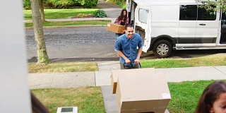 在家庭搬家的日子里，孩子帮助从货车上卸下箱子